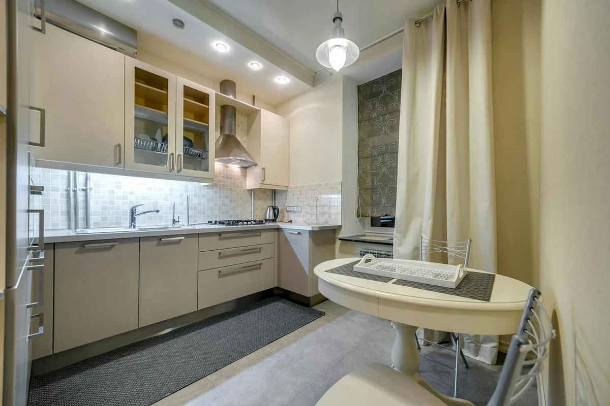 Elegante Kücheneinrichtung mit modernen Beige-Schränken und schlankem Essbereich