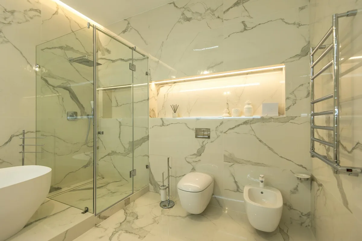 Baño de lujo con mármol, ducha de cristal y accesorios modernos