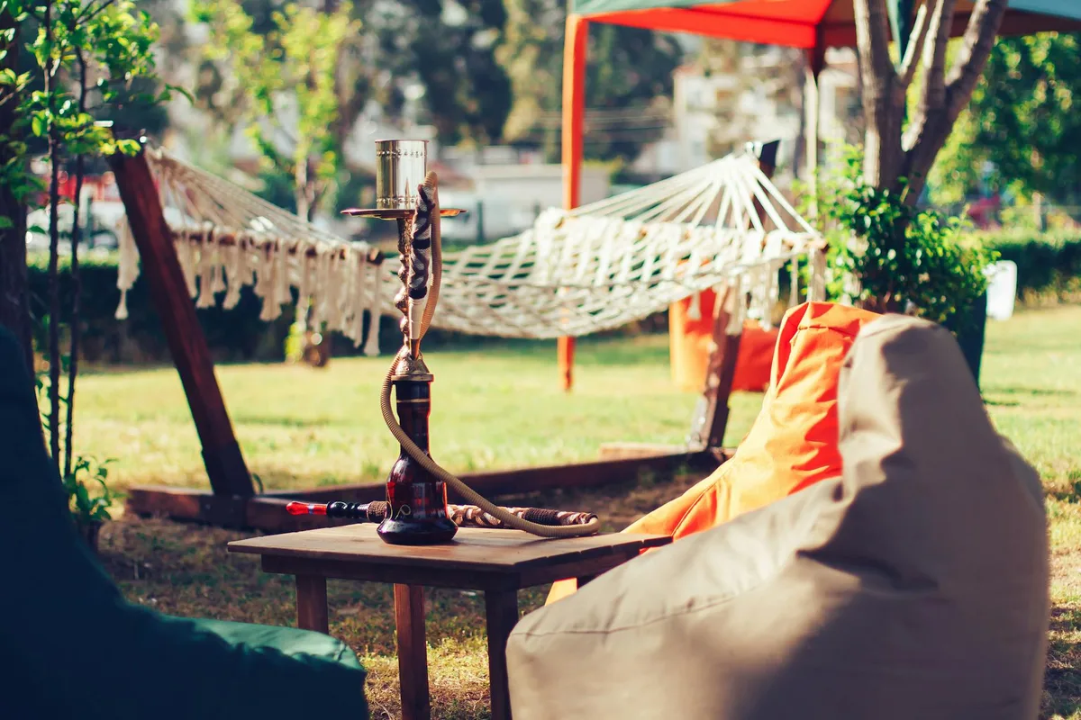 Narguilé sur table en bois dans un café extérieur cosy avec hamac