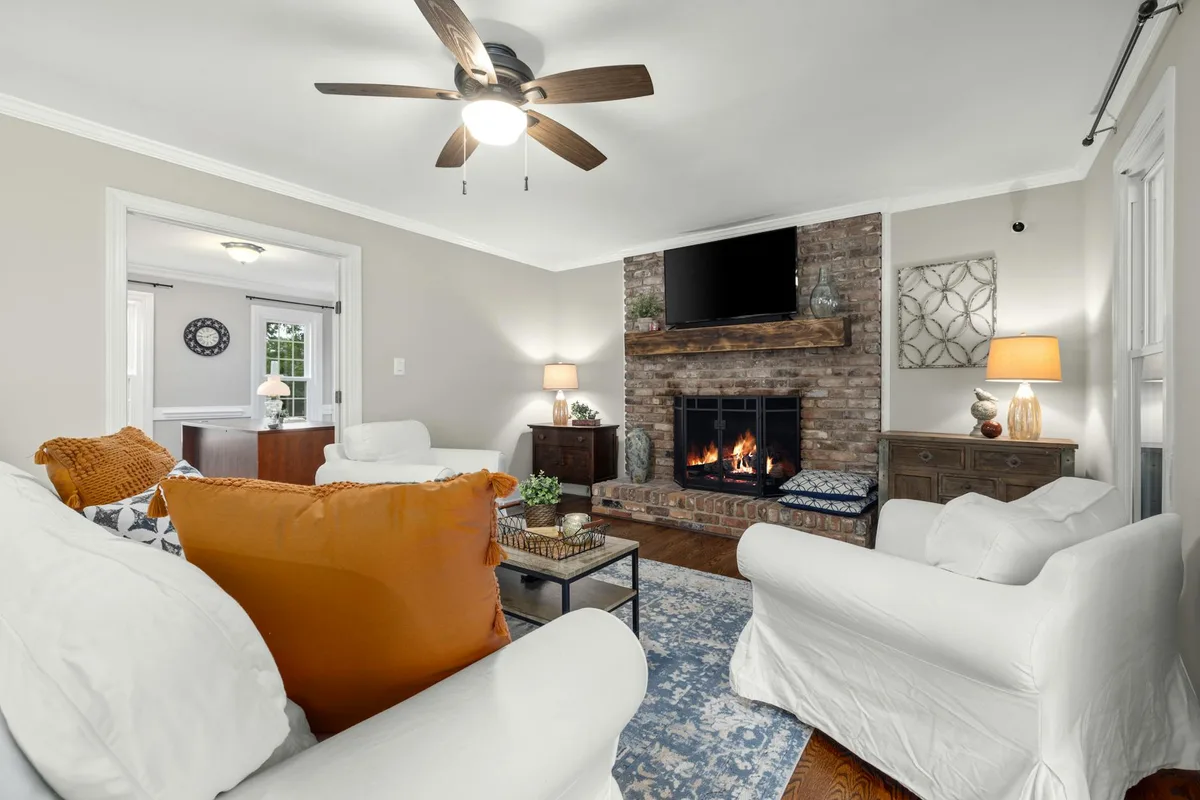 Einladendes Wohnzimmer mit warmem Ziegelkamin, orangefarbenen Akzenten und klassischer Dekoration