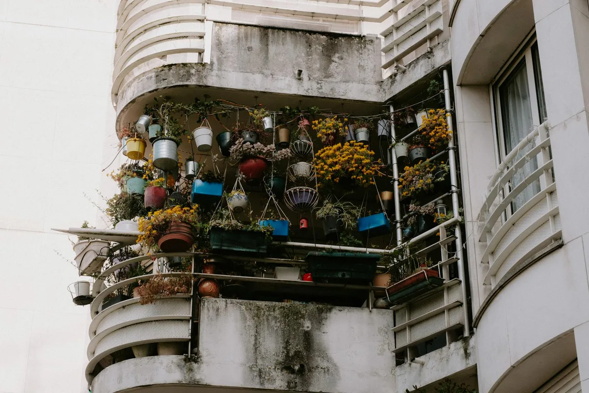 Vista dal basso di un balcone rigoglioso di piante in vaso su una facciata di edificio