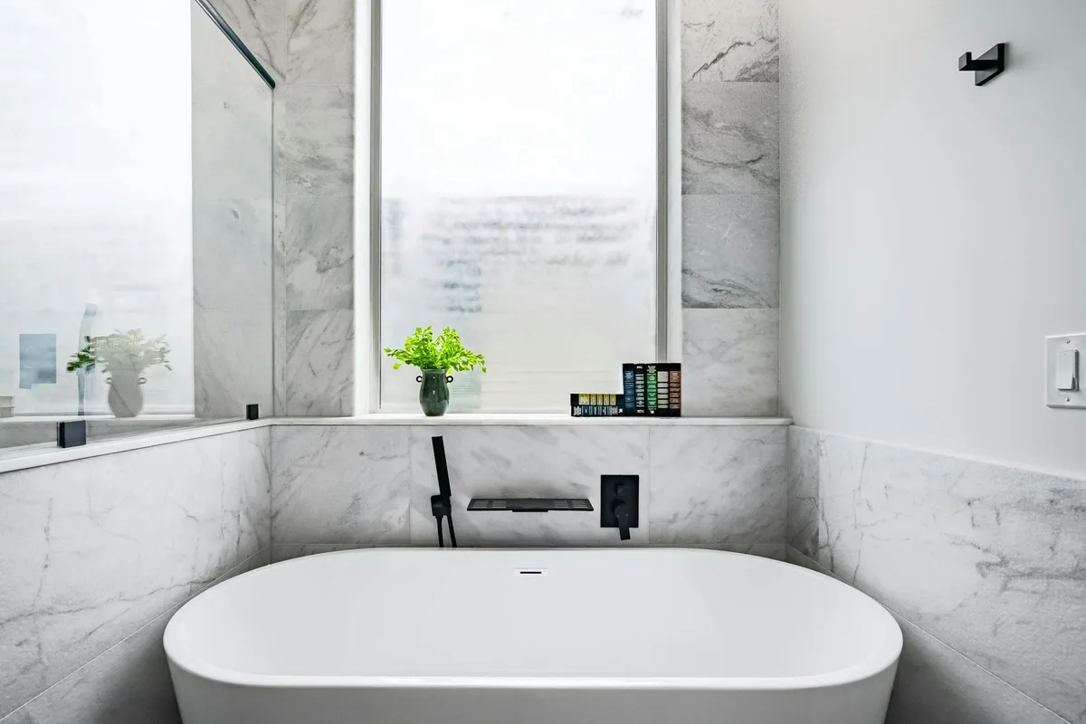 Luxuriöses Marmorbad mit weißer Badewanne und minimalistischer Dekoration