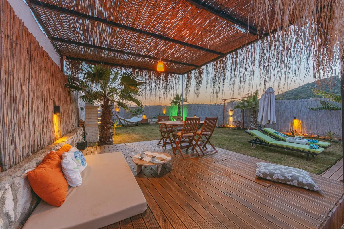 Terrasse tropicale extérieure luxueuse avec palmiers et pont en bois au coucher du soleil, parfaite pour la détente