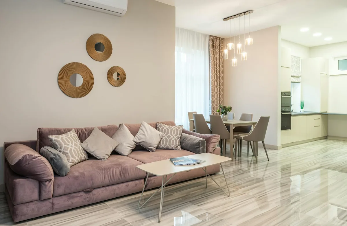 Modernes Wohnzimmer mit bequemem Sofa und Küche mit Einbaugeräten