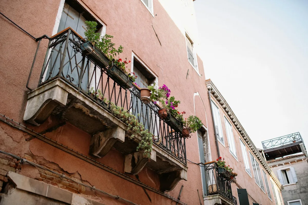 Rustic balconies adorned with vibrant floral arrangements on a Mediterranean townhouse.