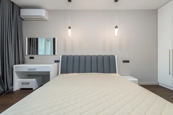 Camera da letto minimalista con letto imbottito, lampade a sospensione e arredi moderni