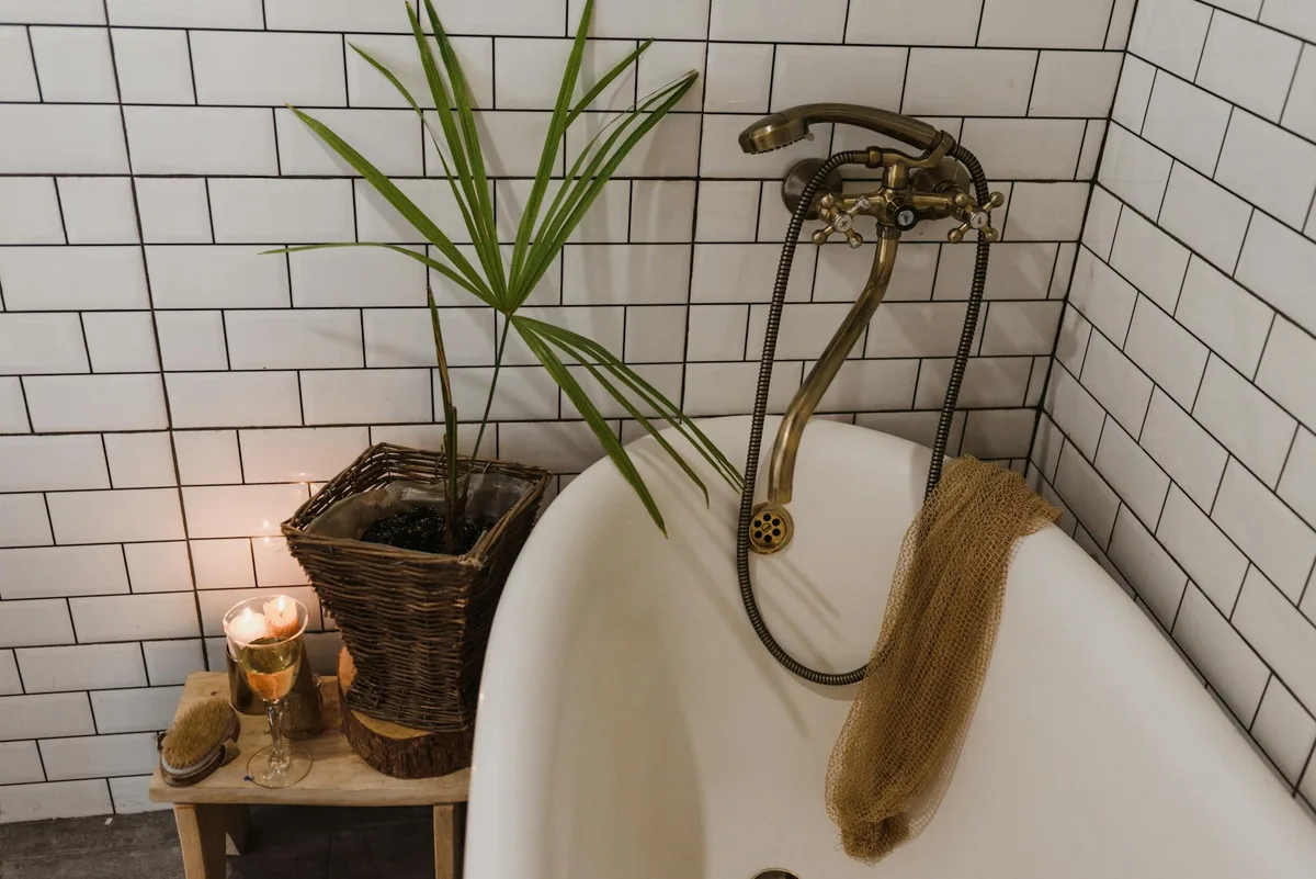 Stilvolles Badezimmer mit eleganter Badewanne, Weidenkorb und Zimmerpflanze für eine gemütliche Atmosphäre.