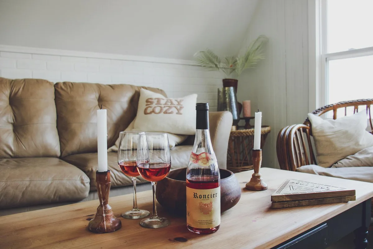 Warm and cozy living room setup with wine, candles, and a comfortable couch.