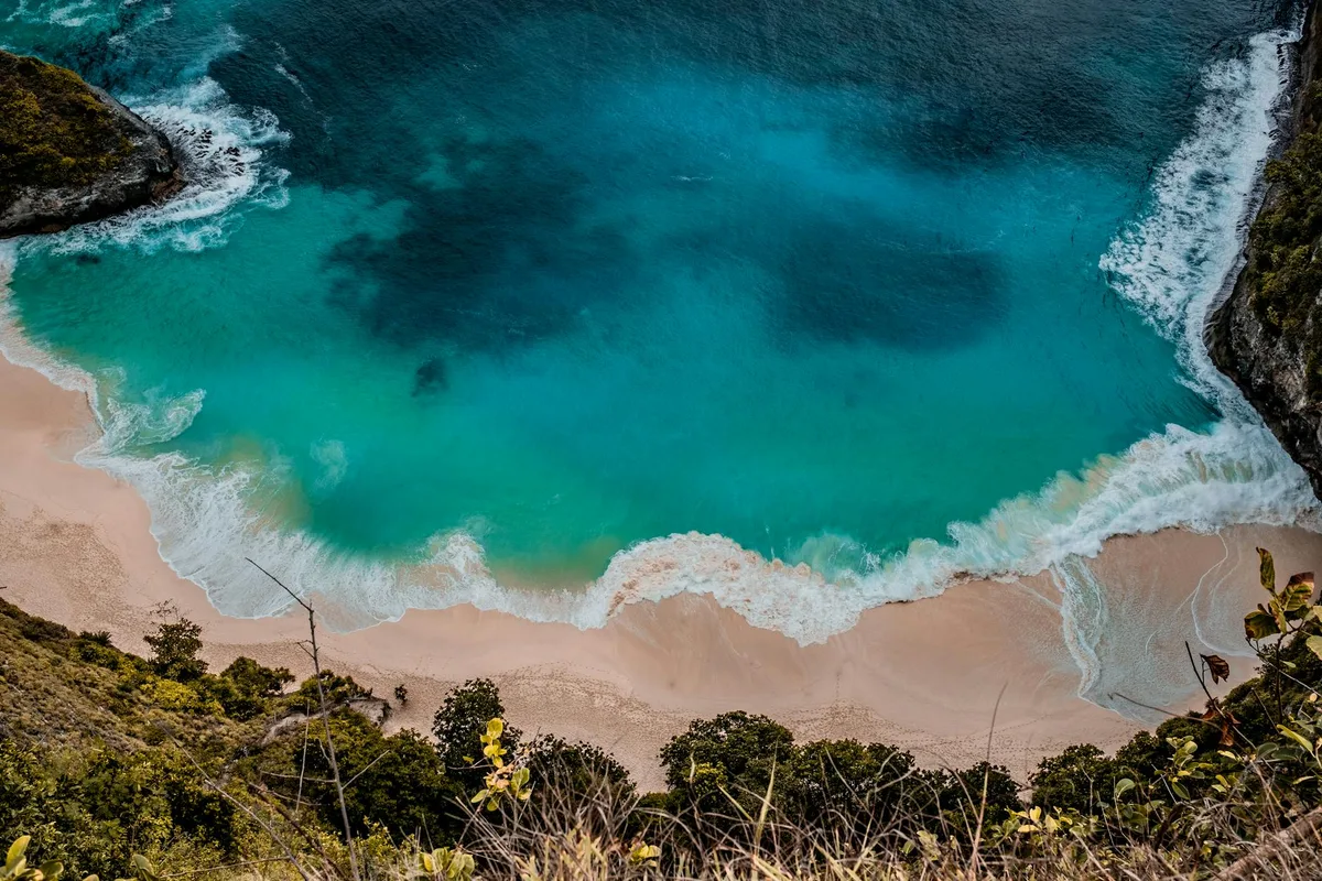 Luftaufnahme eines türkisblauen Strandes mit Wellen in Bali, Indonesien