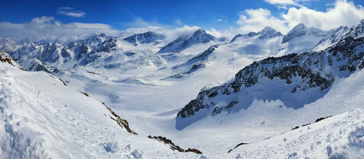 Catena montuosa innevata con cielo blu e nuvole