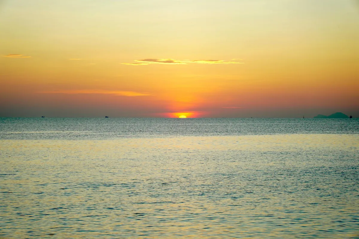 Vista oceanica tranquilla al tramonto con cieli dorati e arancioni