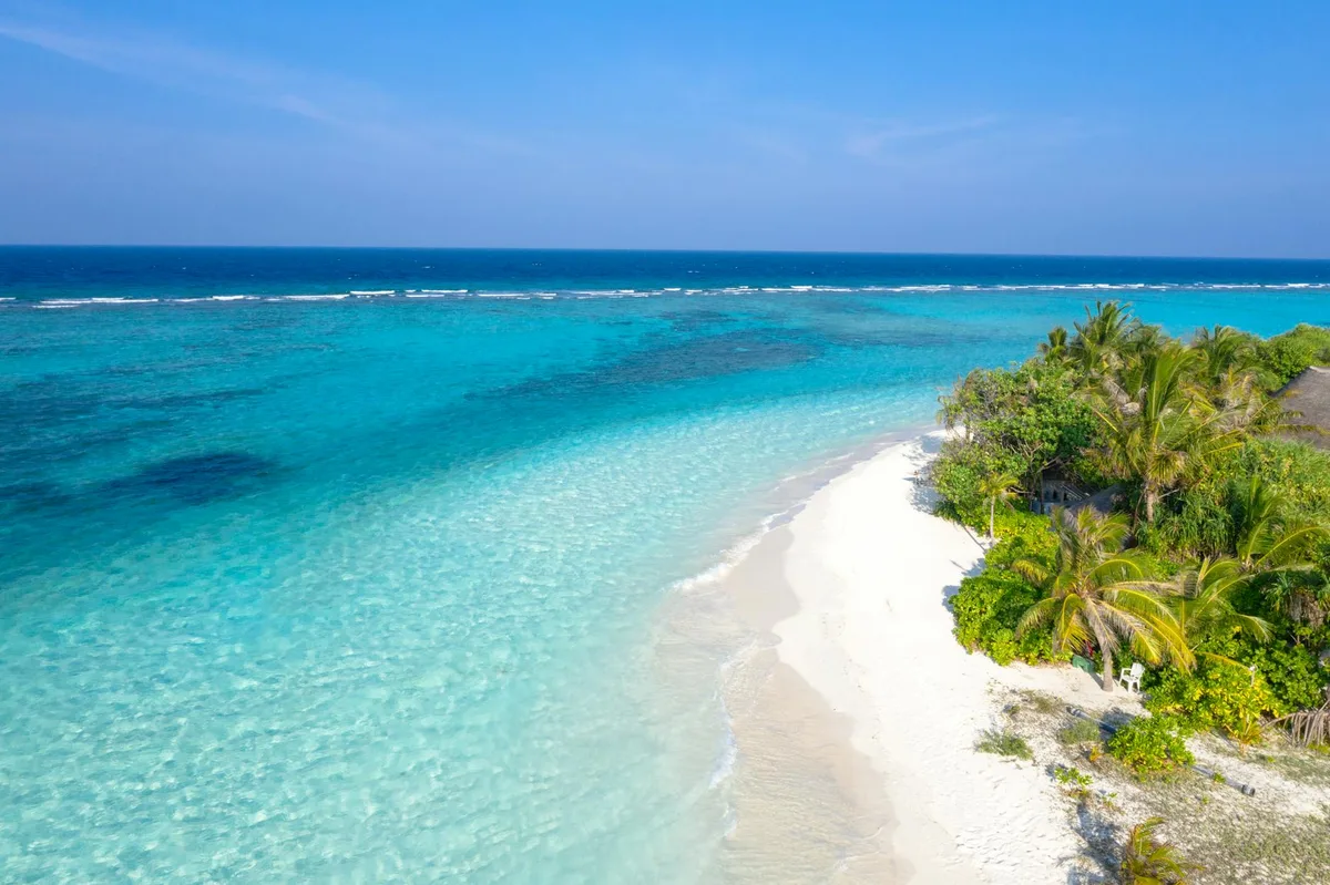 Spiaggia tropicale con acqua cristallina e vegetazione lussureggiante, fuga serena