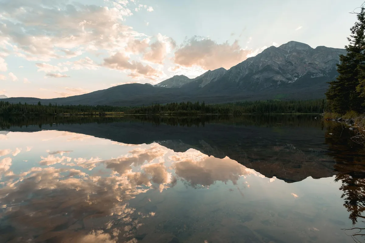 Tramonto mozzafiato su un lago sereno nel Parco Nazionale Jasper, Canada, che riflette le Montagne Rocciose