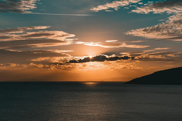 Tramonto mozzafiato sull'oceano con nuvole drammatiche e tonalità dorate