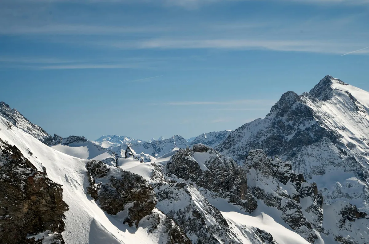 Montagne rocciose innevate sotto un cielo azzurro limpido, panorama mozzafiato