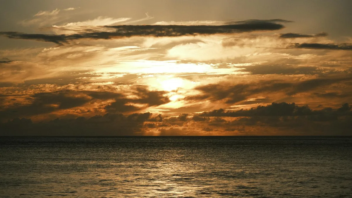 Tramonto oceanico con nuvole infuocate e onde calme