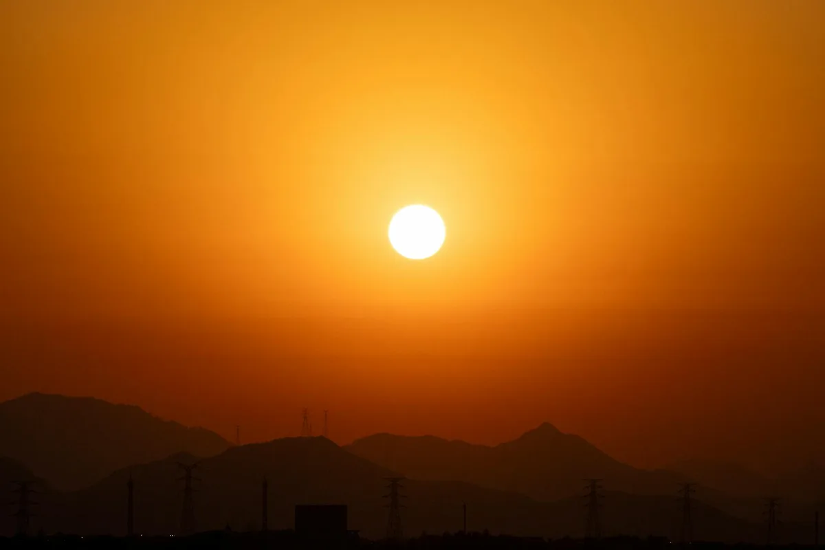 Sonnenuntergang über silhouettenhaften Bergen mit Stromleitungen