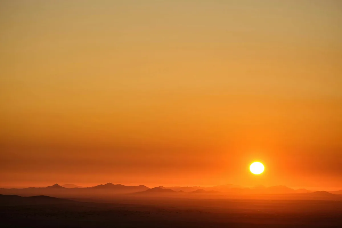 Faszinierender Sonnenuntergang über weiten Wüstendünen, der Ruhe mit warmen, goldenen Farbtönen hervorruft