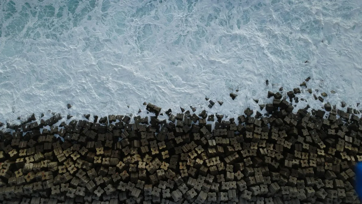 Drohnenaufnahme von Wellen an geometrischen Betonwellenbrechern auf Madeira