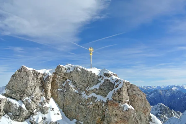 Goldenes Gipfelkreuz auf der Zugspitze zwischen Schnee und Fels in Garmisch-Partenkirchen