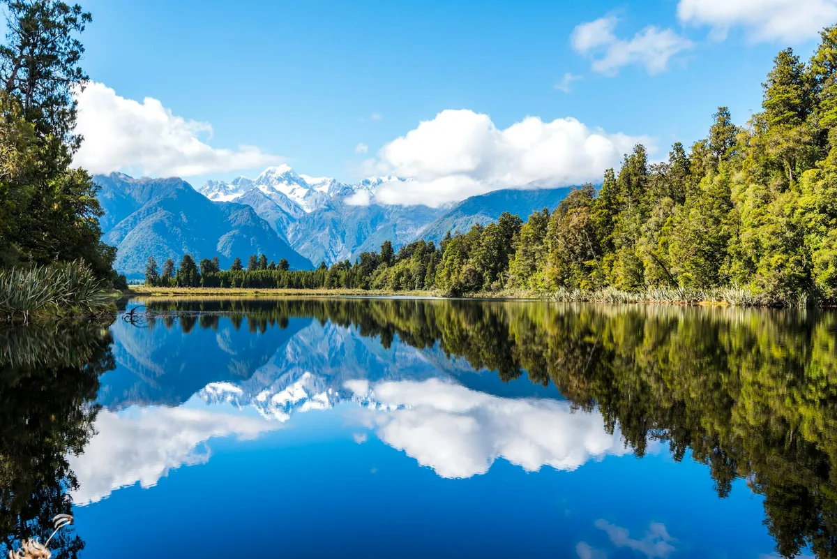 Lago di montagna sereno con riflessi e foresta circostante