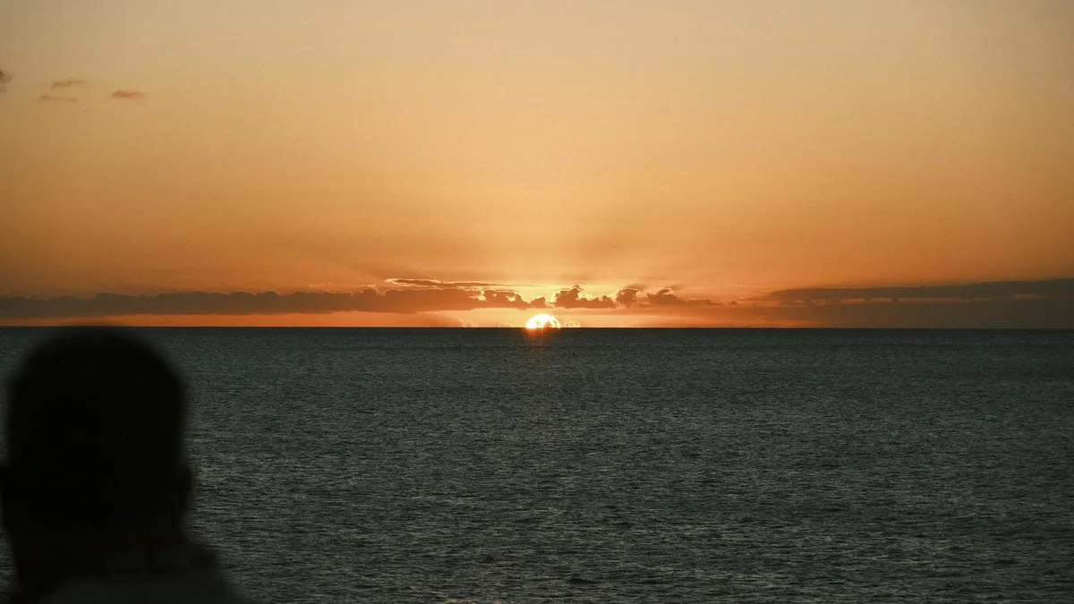 Friedlicher Sonnenuntergang über dem Ozean mit silhouettiertem Beobachter, Ruhe und Gelassenheit