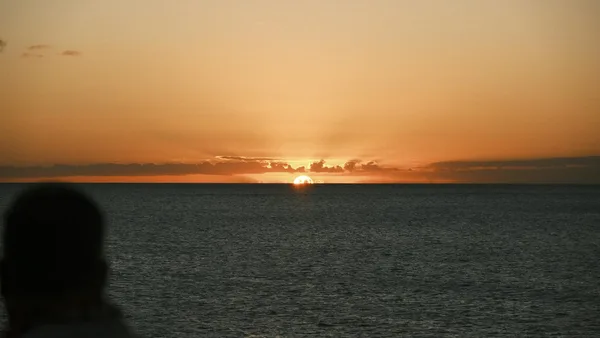 Tramonto sereno sull'oceano con osservatore in silhouette