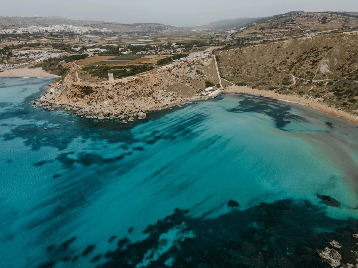 Luftaufnahme der Küste von Mgarr, Malta: Blaues Wasser und Felsen
