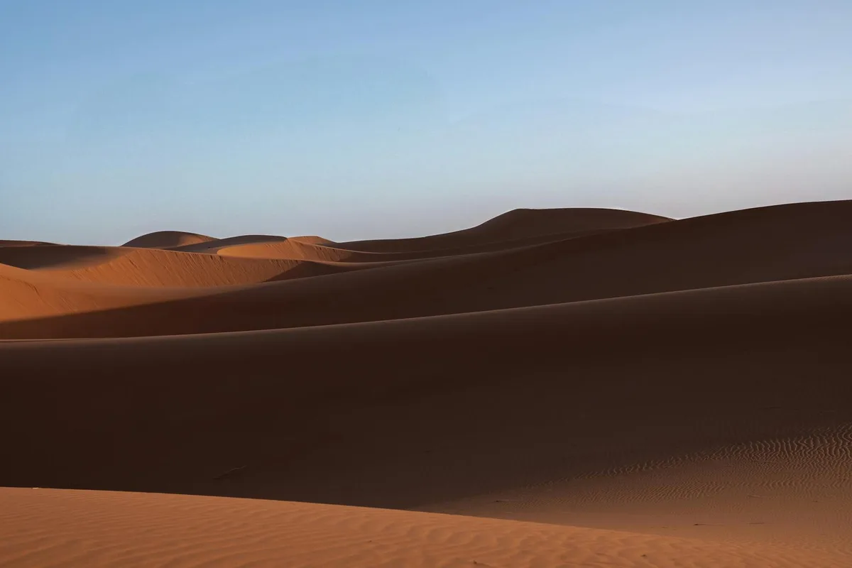 Paesaggio desertico sereno con dune dorate sotto un cielo mattutino limpido