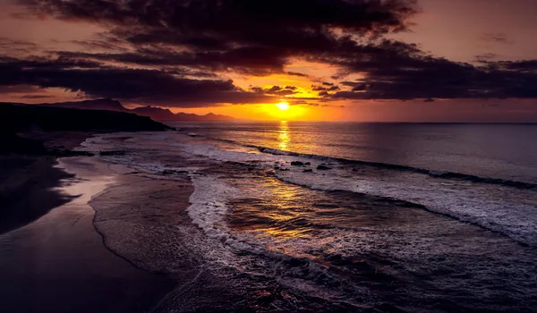 Tramonto sereno con nuvole drammatiche sulle onde dell'oceano