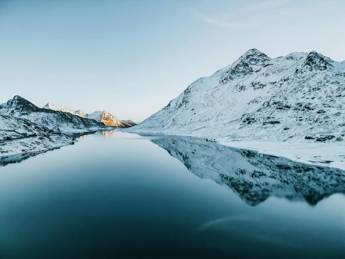 Schneebedeckte Berge spiegeln sich in einem ruhigen See, Winter der Schweizer Alpen