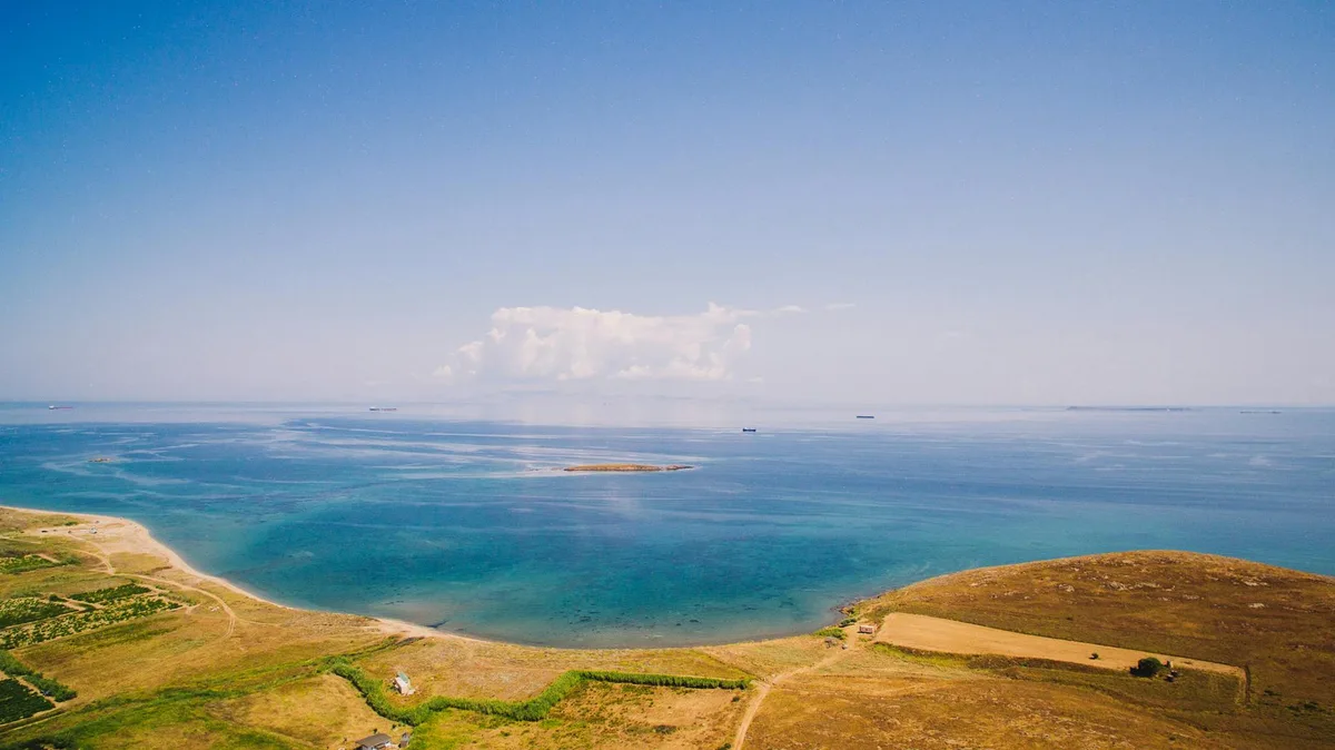 Ripresa aerea di una costa serena con acque cristalline e paesaggio vibrante