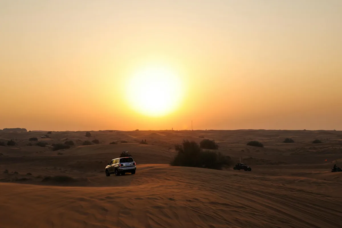 Tramonto nel deserto con SUV tra le dune: avventura e serenità