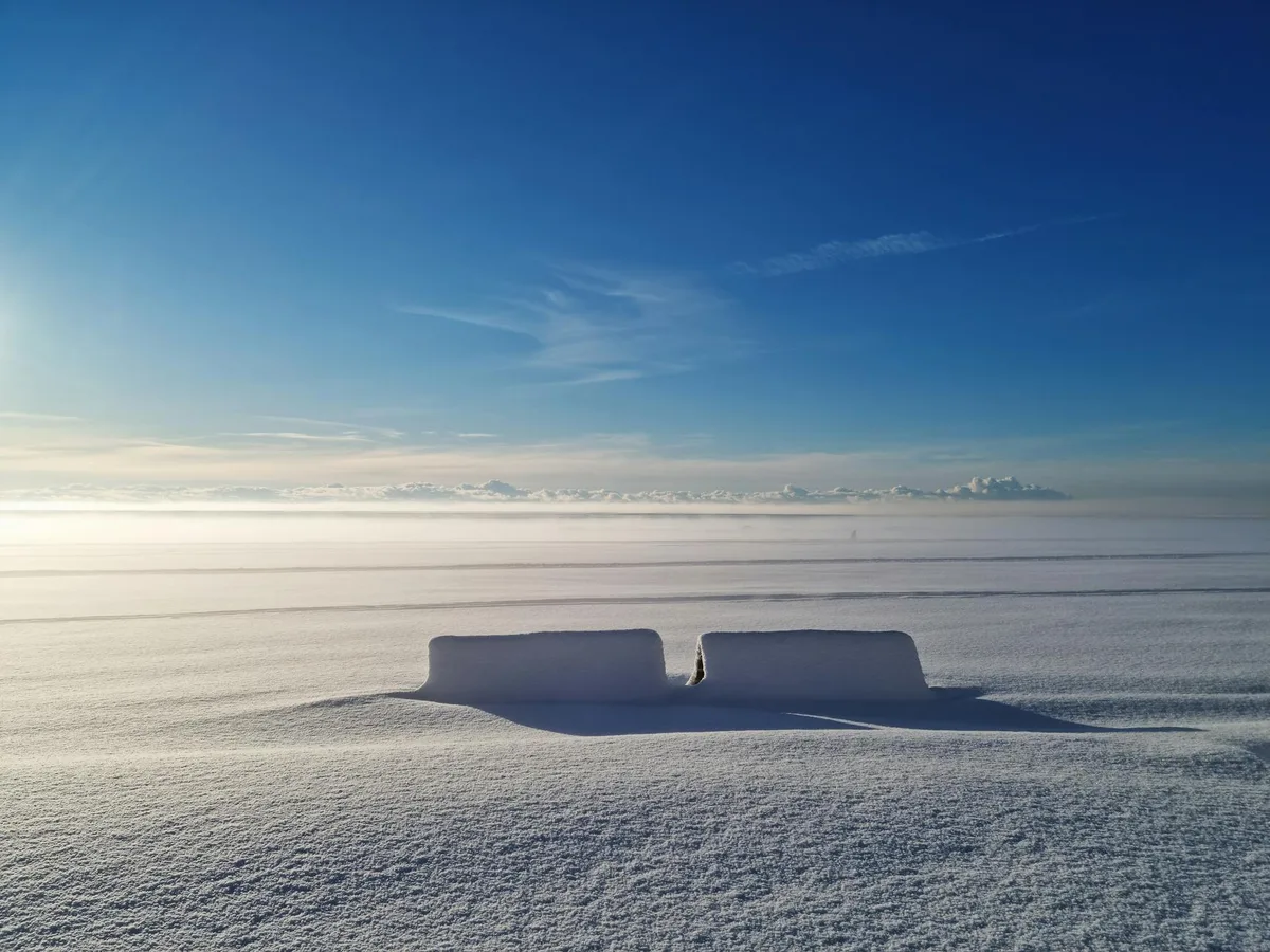 Campo innevato tranquillo sotto cielo azzurro a Pärnu, Estonia, bellezza invernale serena