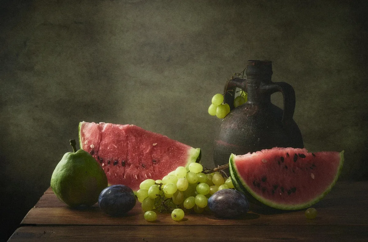 Natura morta classica con anguria, uva, pera, prugne e ceramiche su tavolo