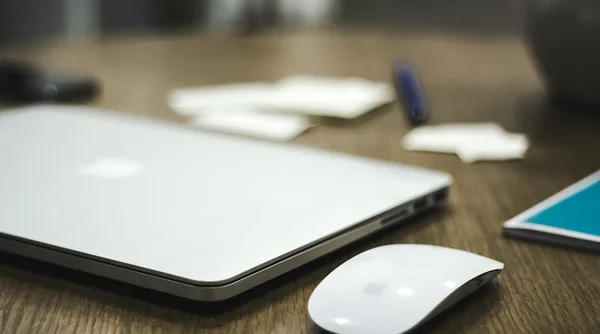 Spazio di lavoro minimalista con laptop chiuso e mouse wireless su scrivania in legno