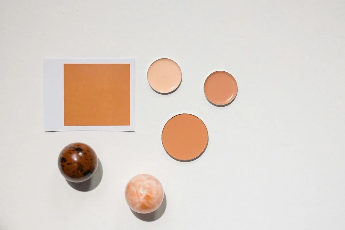 Flat lay minimalista con diverse tonalità di cosmetici su superficie bianca