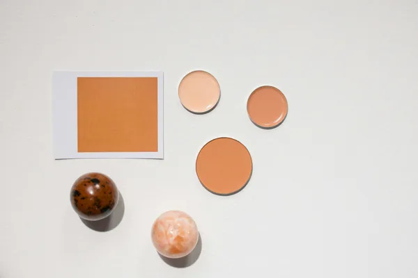 Flat lay minimalista con diverse tonalità di cosmetici su superficie bianca