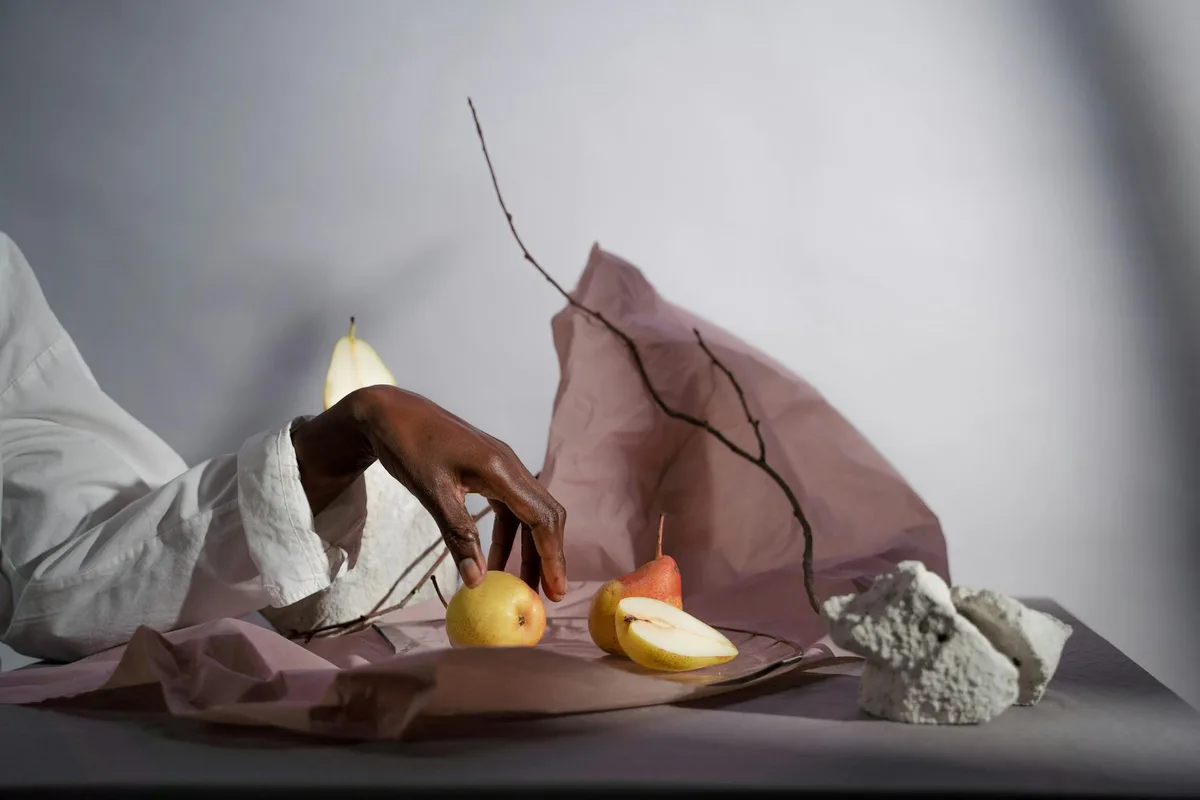 Natura morta creativa con pere, mano e rami su sfondo di carta