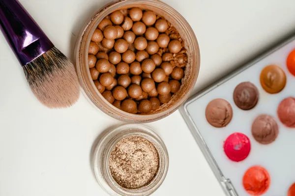 Flat lay con pennelli, perle bronzer e palette labbra per beauty