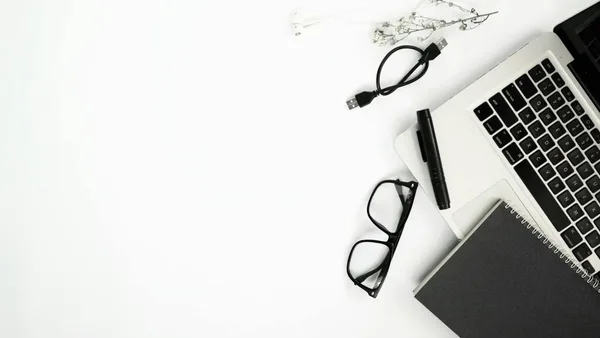 Flat lay minimalista di laptop, occhiali e taccuino su sfondo bianco