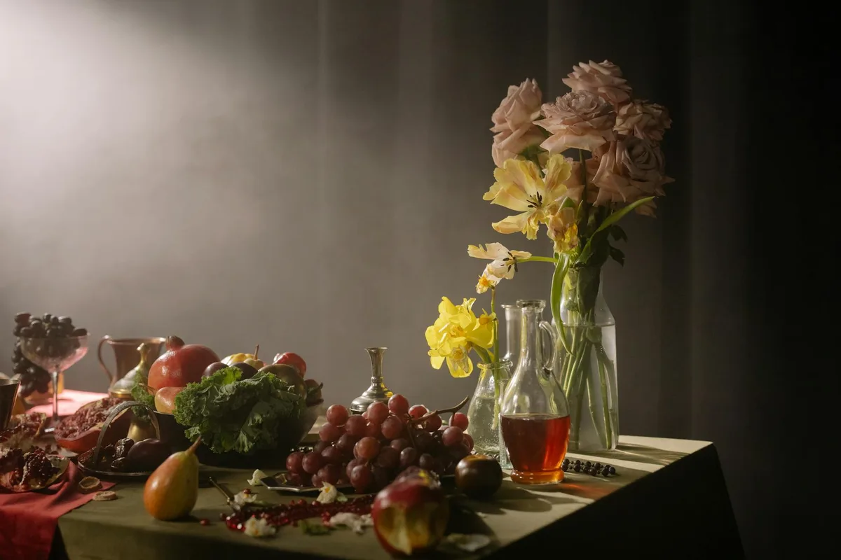 Natura morta classica con frutta e fiori su tavolo con illuminazione soffusa