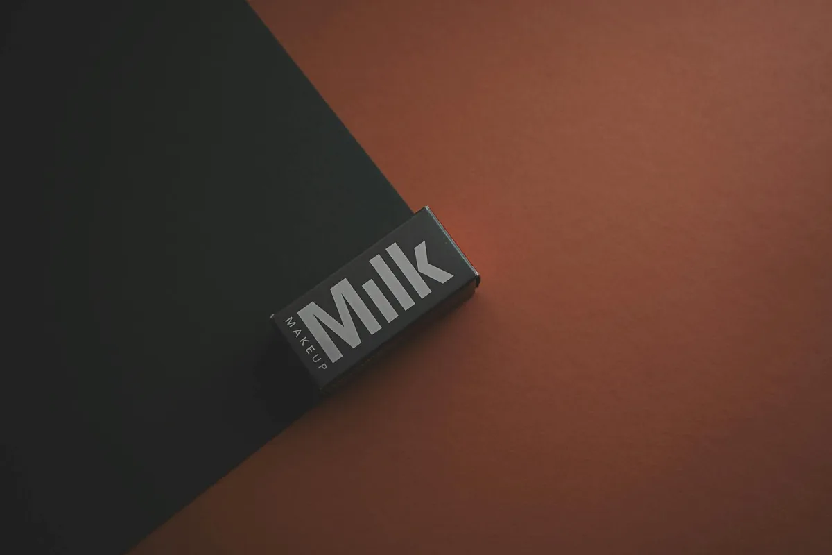 Primo piano scatola Milk Makeup su sfondo scuro. Packaging minimal.