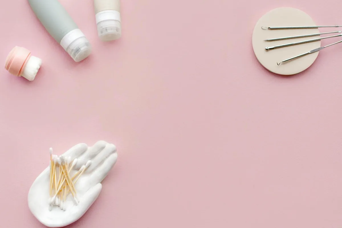 파스텔 핑크 배경에 플랫 레이 스타일로 배열된 스킨케어 도구와 제품 컬렉션