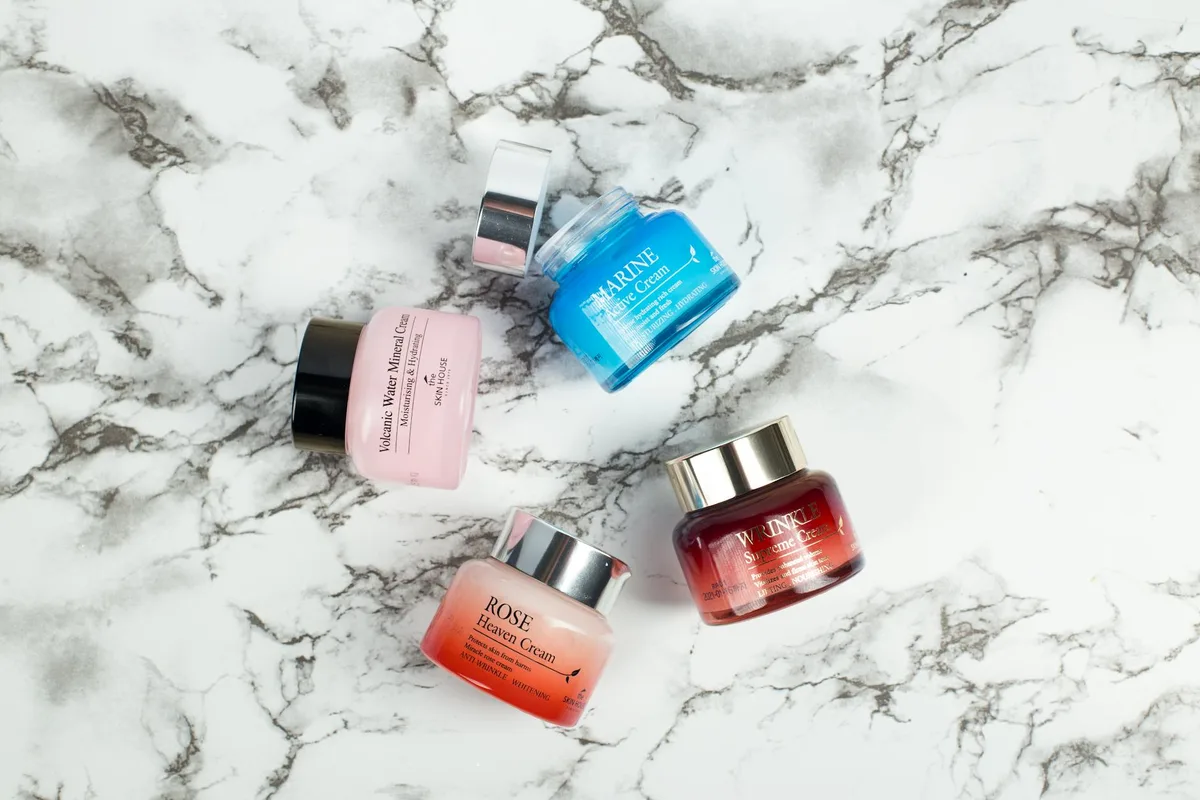 Flatlay: creme skincare eleganti su marmo con colori vivaci.