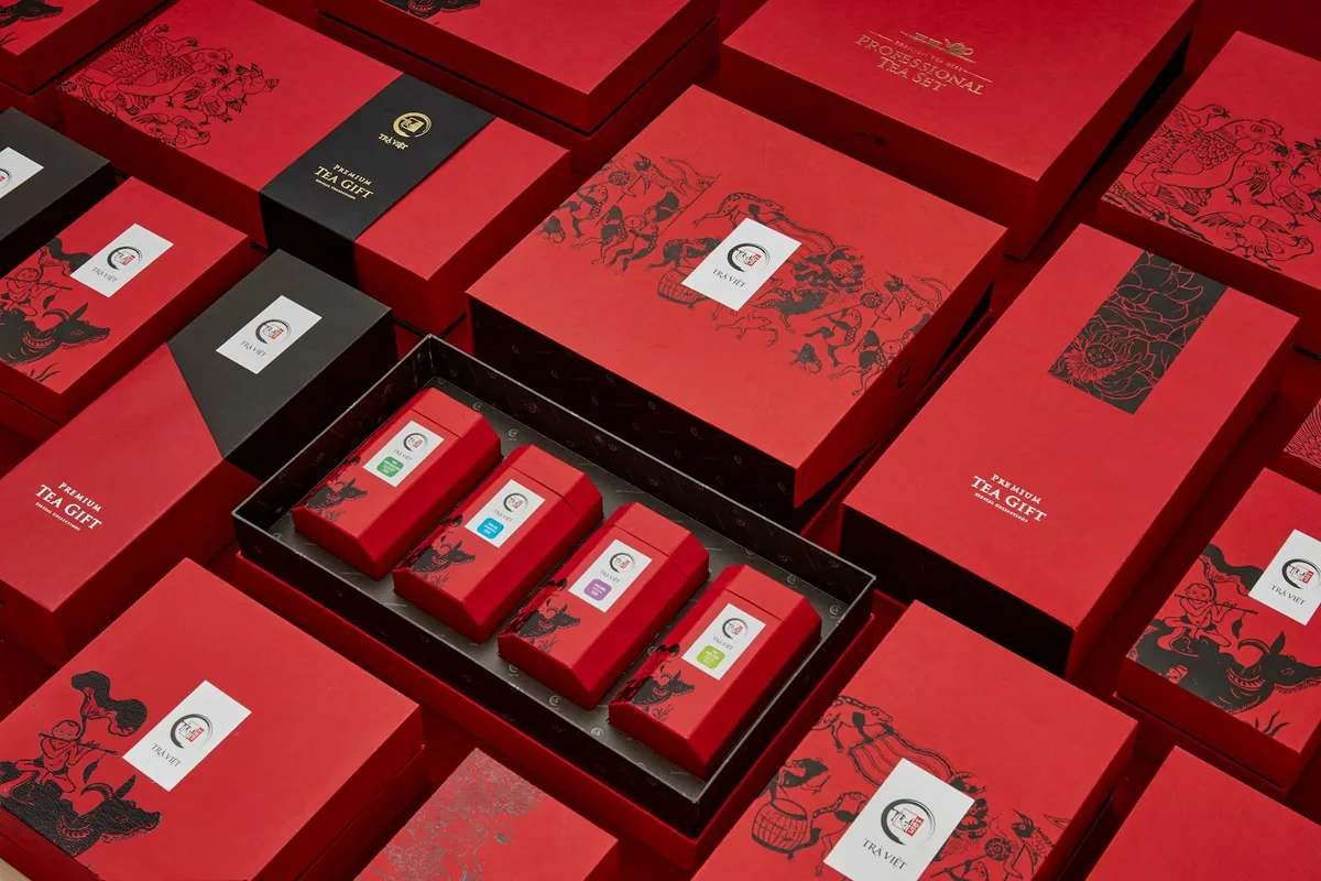 Confezioni regalo tè rosso lussuoso disposte in pattern artistico per occasioni festive