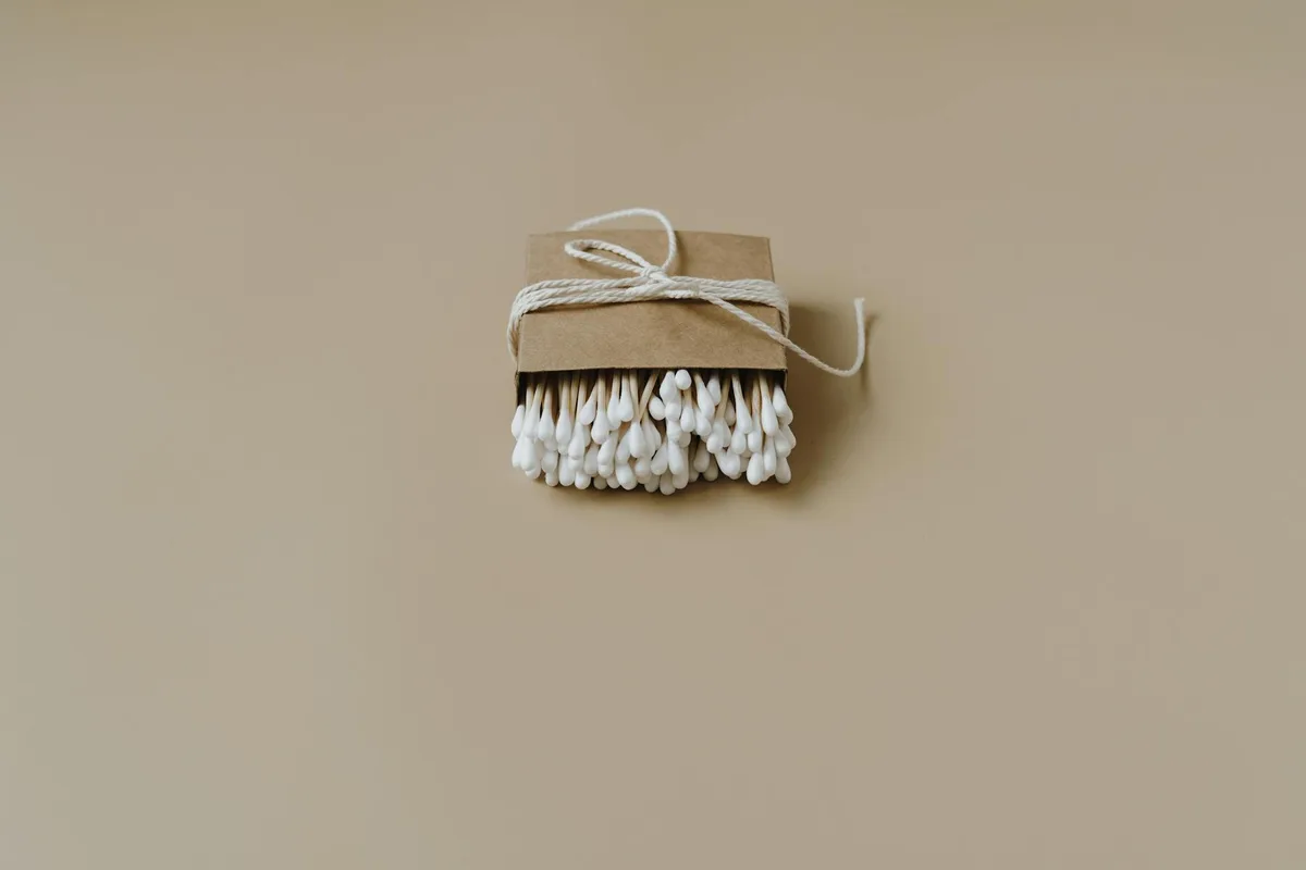 Cotton fioc ecologici minimalisti avvolti in carta riciclata su superficie beige