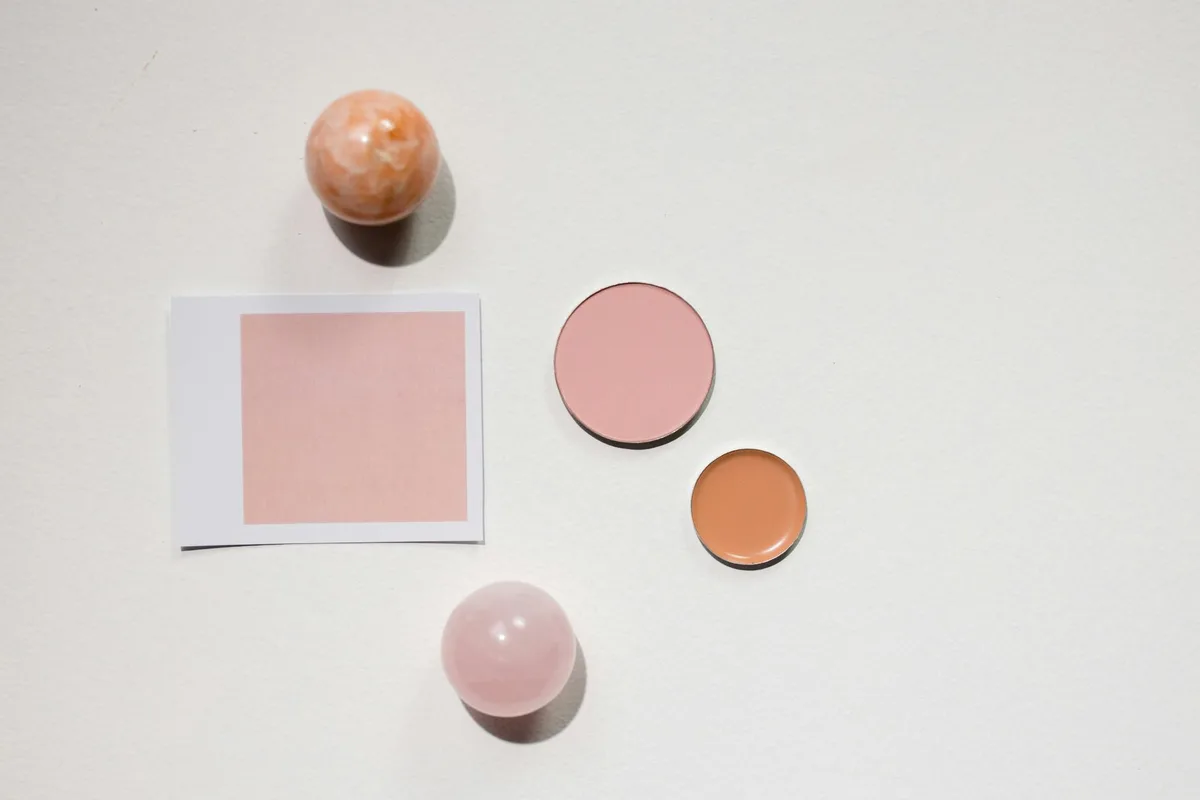 Flat lay minimalista con prodotti makeup e sfere di marmo su superficie bianca