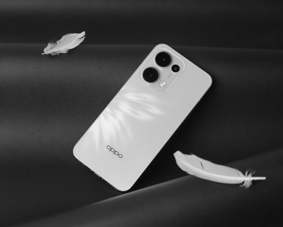 Smartphone bianco minimalista con piume su superficie nera, estetica moderna