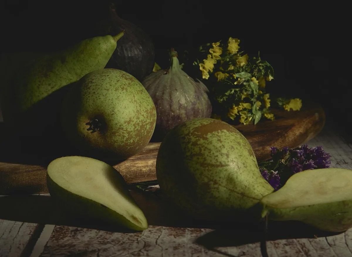 Stimmungsvolles Stillleben mit Birnen, Feigen und Blumen auf einem Holzbrett